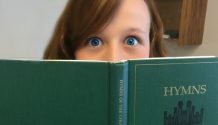 Girl's face behind LDS hymnal