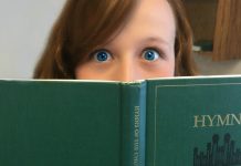 Girl's face behind LDS hymnal