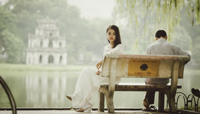 man and woman sitting on bench turned away from each other