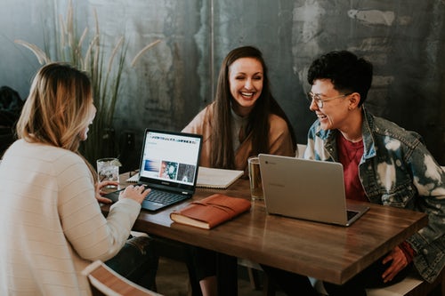 Three hip people sitting and laughing with computers