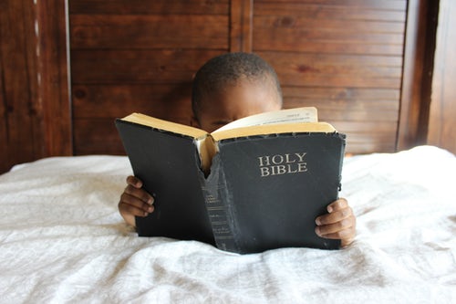 Little boy reading old Holy Bible