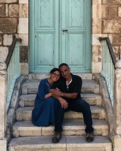 Father and daughter sitting on stairs in front of blue door.