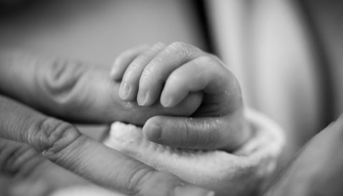 mother holding infant's hand