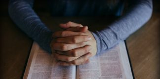 Man folding hands over scriptures