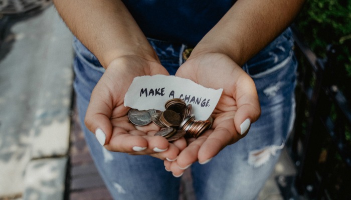 Hands holding coins and paper saying 