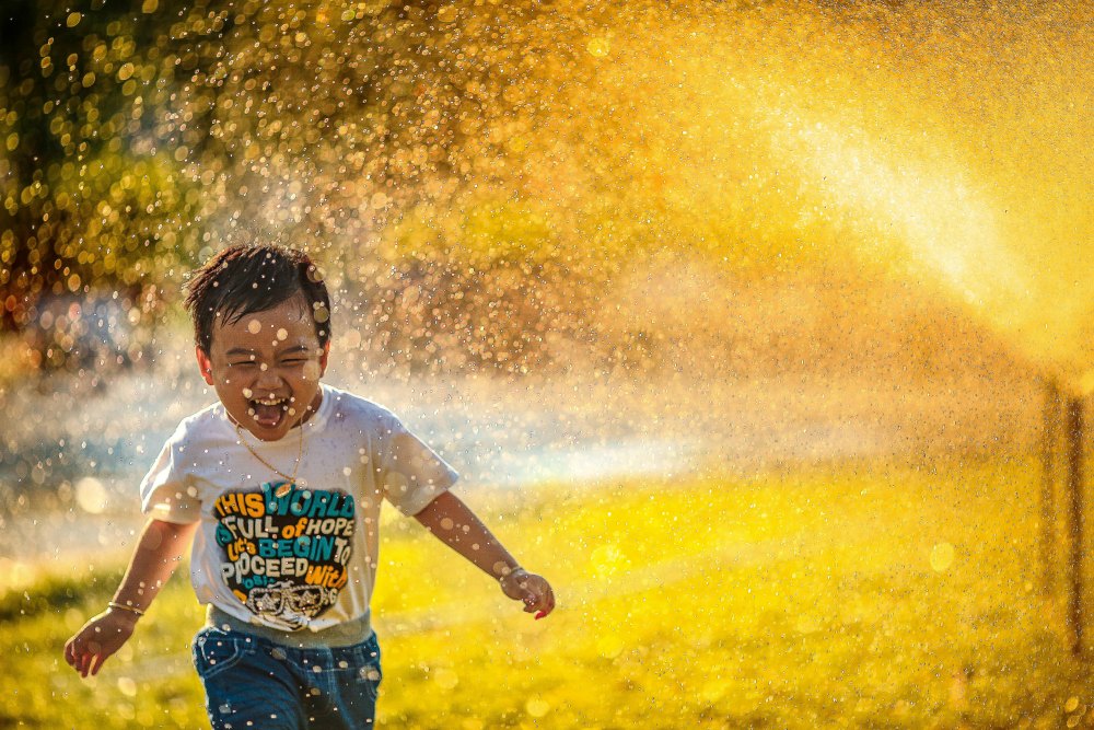 happy kid running through sprinklers mormon