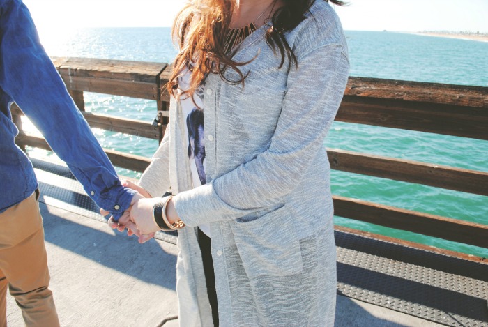 woman reaching for man's hand on pier