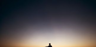 Silhouette of man sitting on bench.