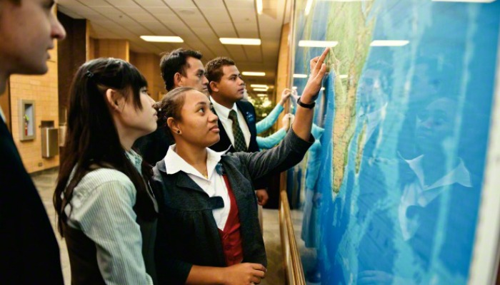 Grupo de misioneros lds apuntando al mapa de la pared