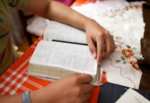 Manos del joven leyendo las escrituras en una mesa