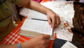 Young person's hands reading scriptures on a table