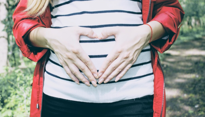 pregnant woman with hands in heart shape