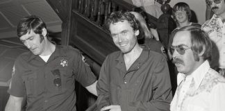 ted bundy being escorted by a police officer