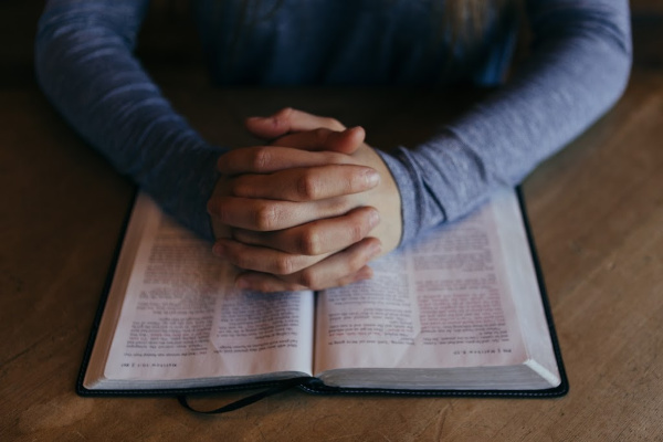 folded hands over scriptures in prayer