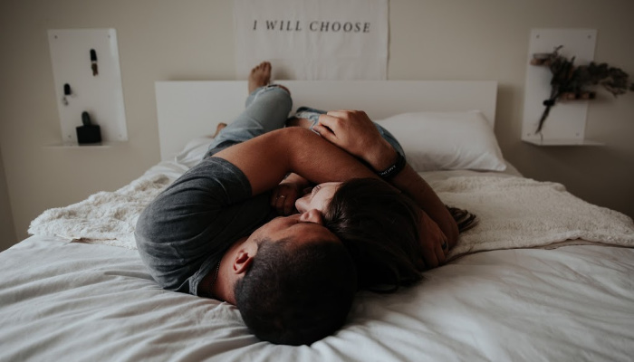 man and woman cuddling in bed