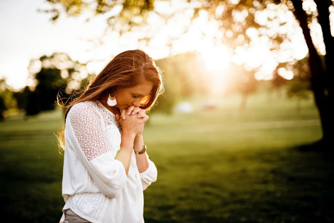 woman praying beside a tree