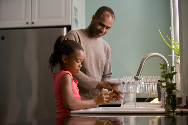 father and daughter washing their hands together at home