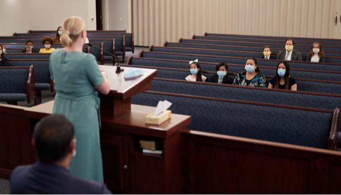 Woman speaking in Church while members practice social distancing.