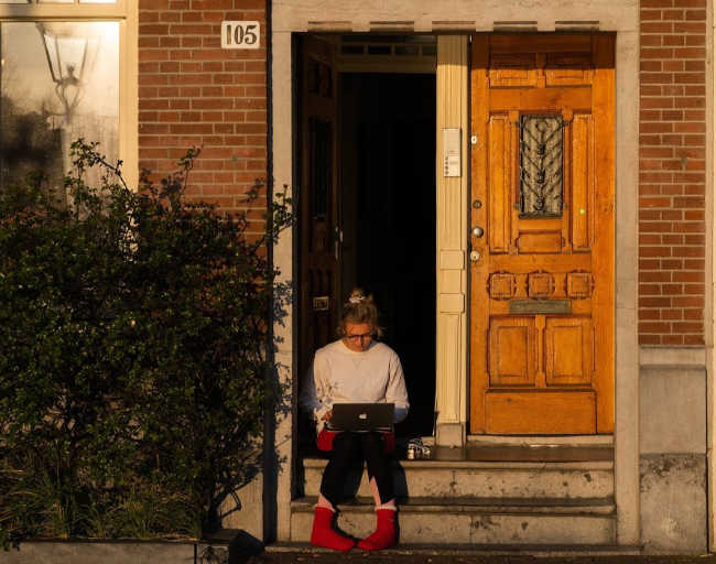 woman working from home on her steps outside apartment