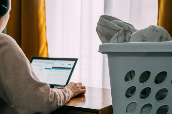 woman working from home with laundry next to her