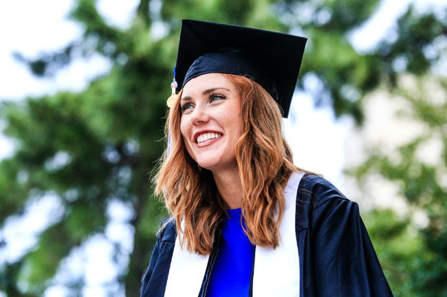 girl graduate wearing cap and gown smiling