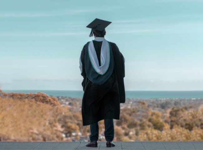 person in graduating cap and gown looking at a view