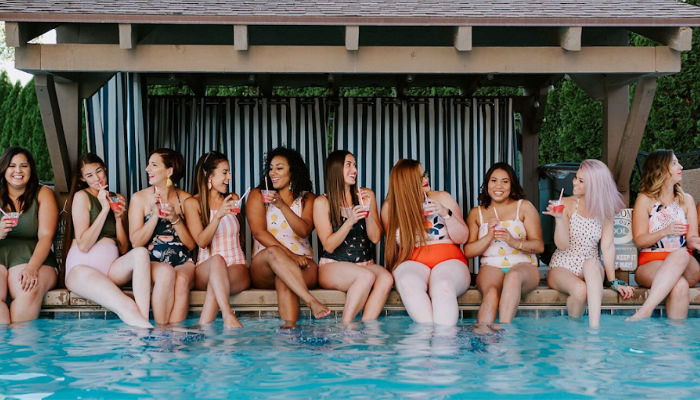 multiple women sitting by pool wearing modest swimsuits