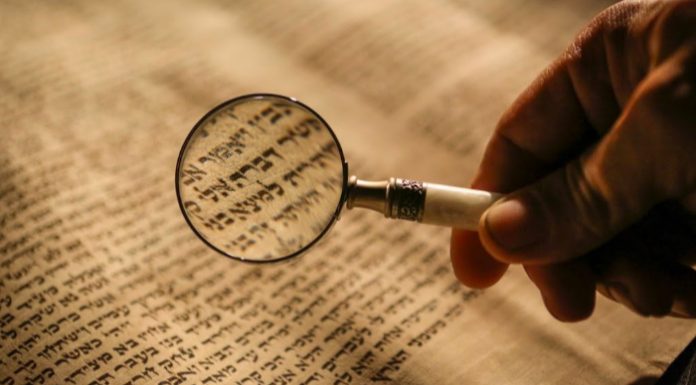 Magnifying glass over Hebrew text.