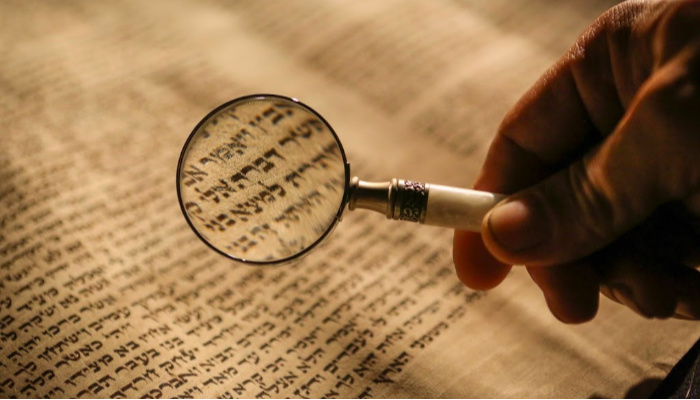 Magnifying glass over Hebrew text.