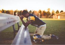 young man football player praying on sideline