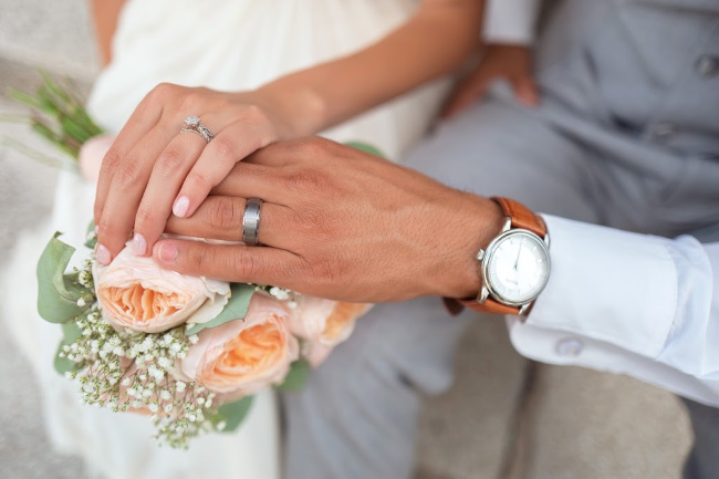 two hands wedding rings on flowers