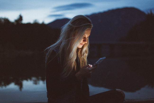 mujer joven, tenencia, teléfono, en la oscuridad, luz, en, ella, cara, por, un, lago