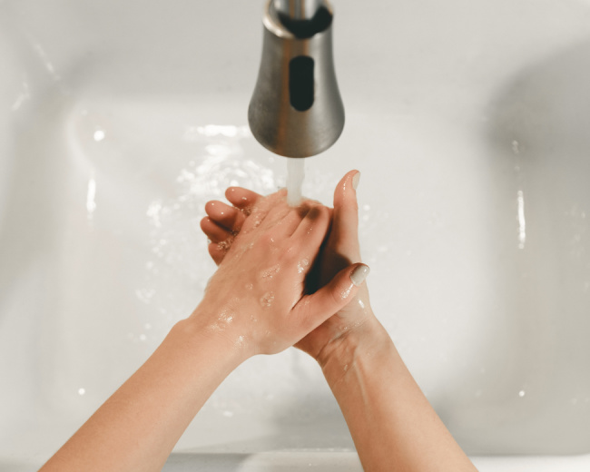 person washing their hands in the sink to avoid covid-19