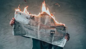 man holding a newspaper that is on fire