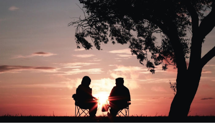 couple sitting together under tree talking