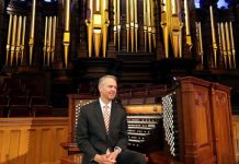 man sitting on organ at temple square for organ concert