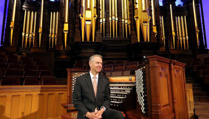 man sitting on organ at temple square for organ concert
