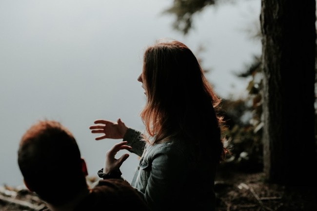 woman talking to man wearing jacket outside