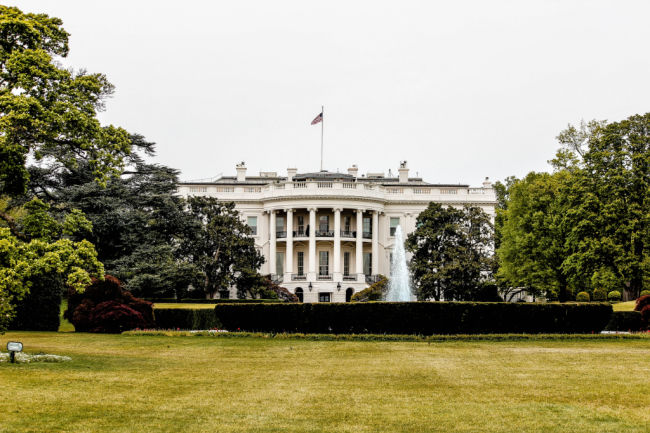 white house with lawn and flag