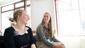 two sister missionaries laughing together sitting down