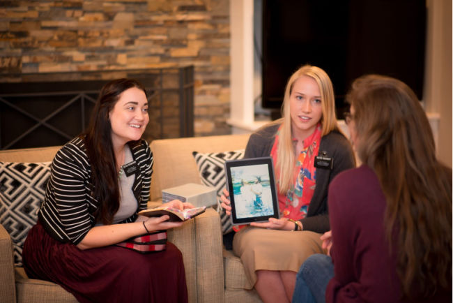 two sister missionaries holding tablet and teaching lesson