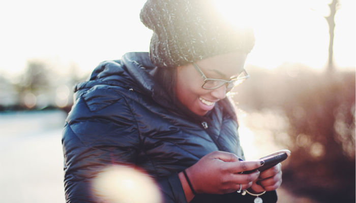 woman smiling at her phone texting and ministering during a pandemic