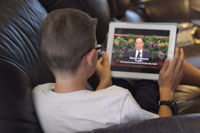 young boy watching general conference on a tablet