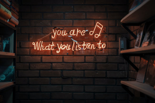 neon sign that says you are what you listen to regarding podcasts