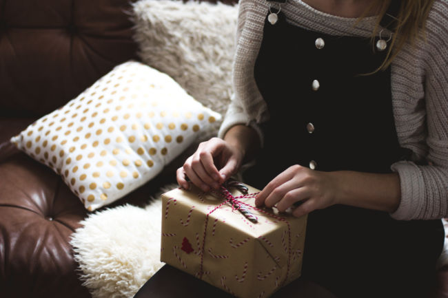 woman opening christmas present with candy cane