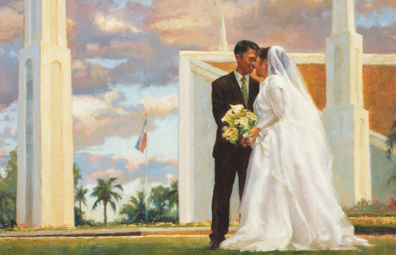 A bride and groom stand in front of the temple.